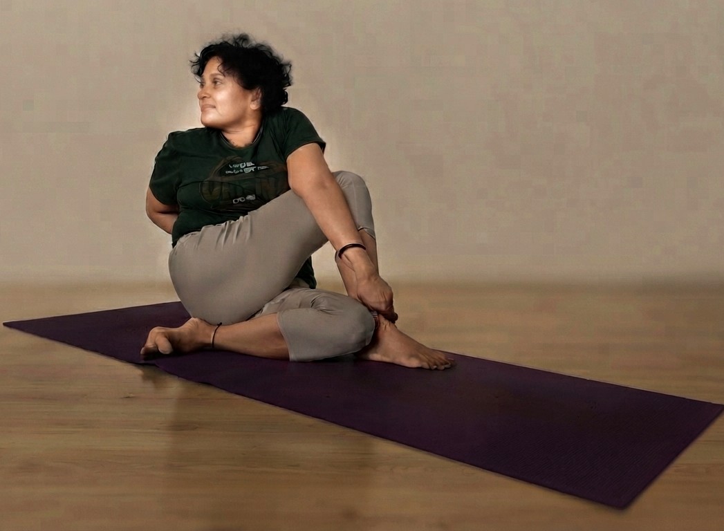 Seated practitioner in Ardha Matsyendrasana, twisting the spine to one side