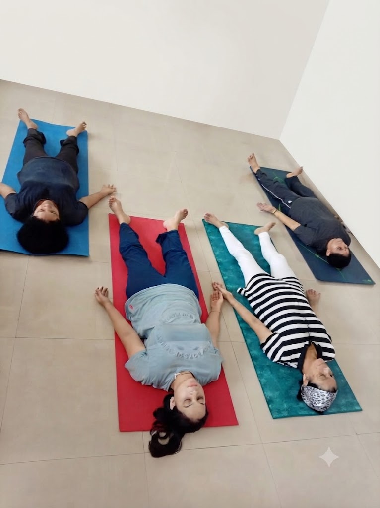 Practitioner lying flat on the back in Shavasana, arms and legs relaxed, in complete stillness