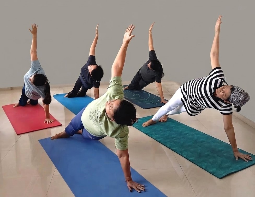 A teacher demonstrating a yoga pose in a bright studio